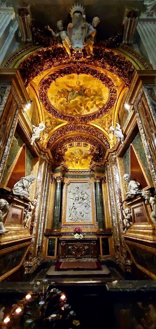 The ceiling fresco depicting the Assumption is by Giuseppe Passeri. He was also responsible for the putti in the pendentives, and the angels bearing Marian symbols in the lunette over the aedicule.