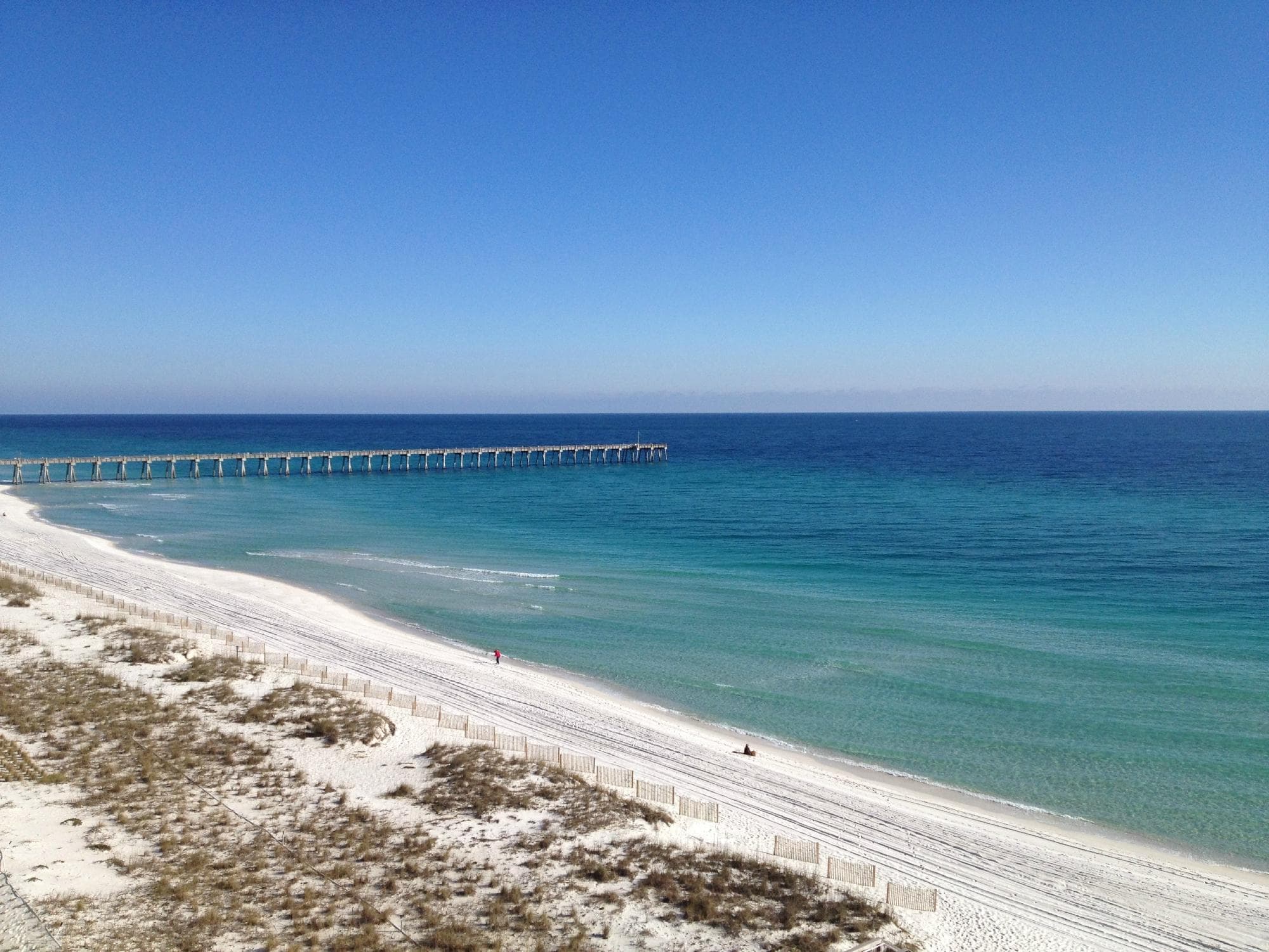 View of the blue water and white sand of Pensacola Beach.
