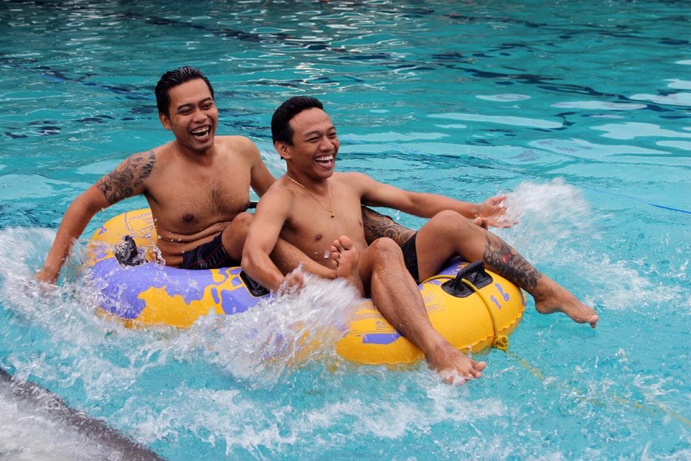 Keseruan peserta outing dalam permainan tarik tambang menggunakan ban di air. 