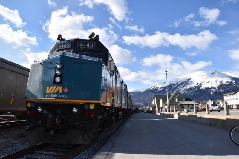 大陸横断鉄道ザ・カナディアン号の先頭機関車と雪をかぶったロッキー山脈。中央の緑の屋根がジャスパー駅舎