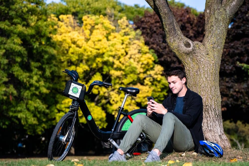Bike Share Toronto rider taking a quick break by a tree to send a text.