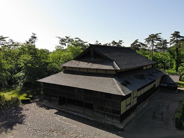 旧広瀬座は福島県伊達郡梁川町の広瀬川川岸に当時の唯一の大衆娯楽施設として、明治20年(推定)に町内の有志によって建てられた芝居小屋です。
舞台中央は回り舞台でその床下には奈落があり、花道・ぶどう棚・ちょぼ席など芝居小屋として必要なものはひと通り構えています。外観も全般にわりあい簡素で古い形式ですが、小屋組には明治中期の建築を反映して、洋風な造り(真束小屋)が採用されました。舞台の裏手は楽屋になっており、板壁には当時来演した役者達の落書きが多数残されています。このような芝居小屋は全国的にみても数棟しか現存していません。