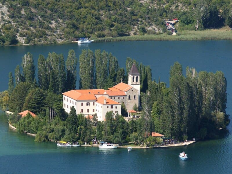 Visovac is an island in the lake of the same name in the Krka National Park, part of the parish of Dubravice.  It is 15 minutes (10 kilometers) away from Skradin, and 10 minutes from Drniš.  On the island there is a church from the 17th century and a Franciscan monastery.  The oldest preserved parts of the complex are the well crown from the 14th century, and parts of the monastery cloister from the 15th century.
