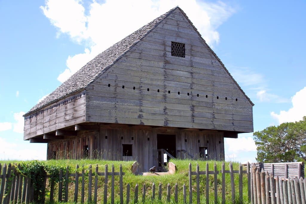 The 3-and-a-half story cypress Blockhouse is the main feature of the British fort. It supports a powder room, gaol cell, gun floor, loophole overhang, and a catwalk high in the gabled roof.