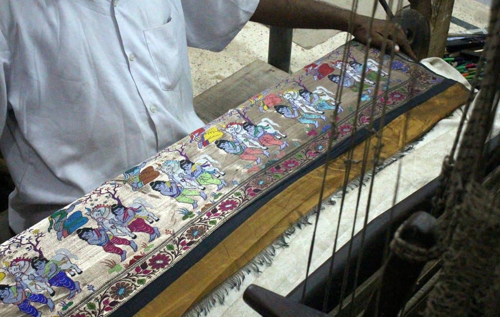 Artesão de seda trabalhando numa peça;