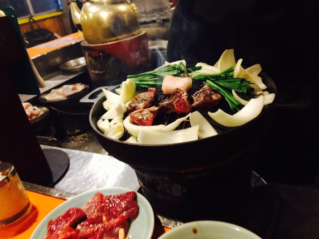 Grilling very tender pieces of lambs around its charcoal fire underneath the iron plate
