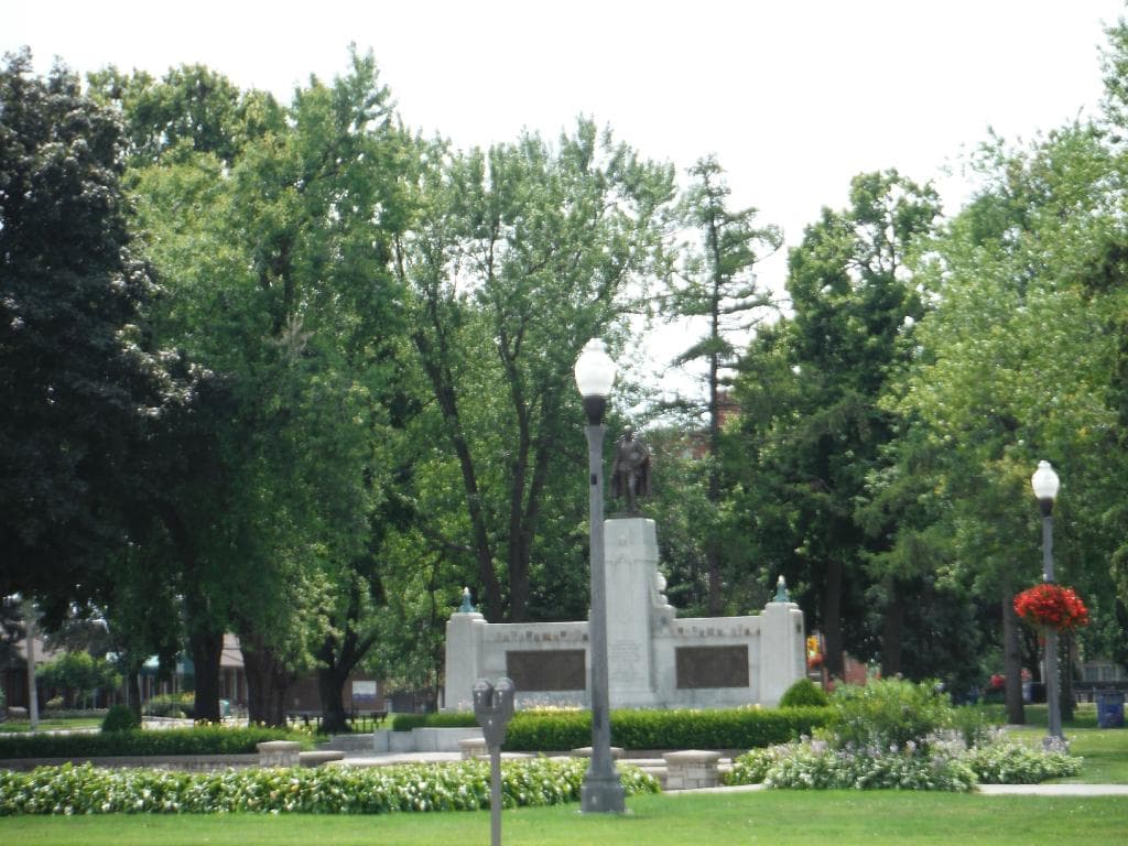 Statue of a man on top of some pilar or stone base.