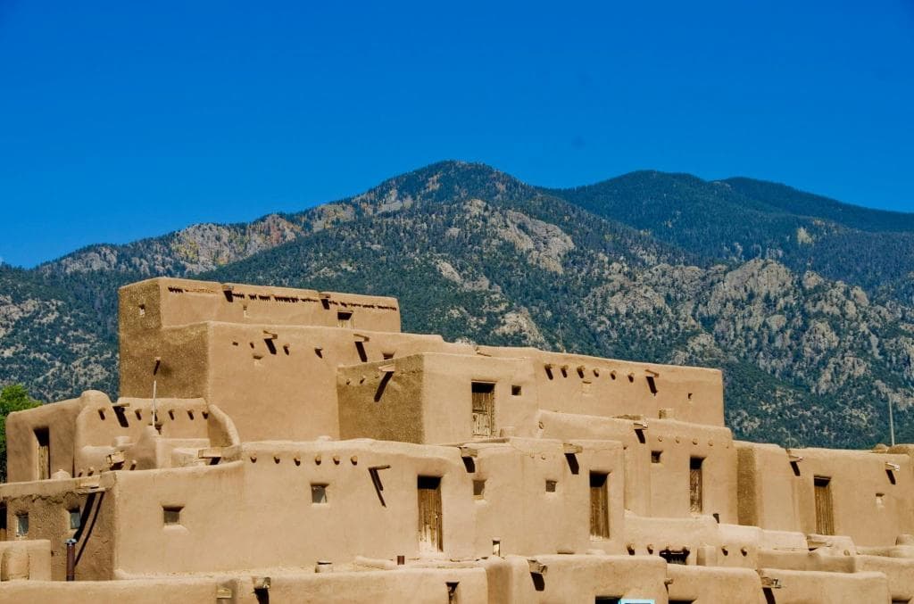 The bright baked walls of Taos Pueblo glow in the morning sunlight.