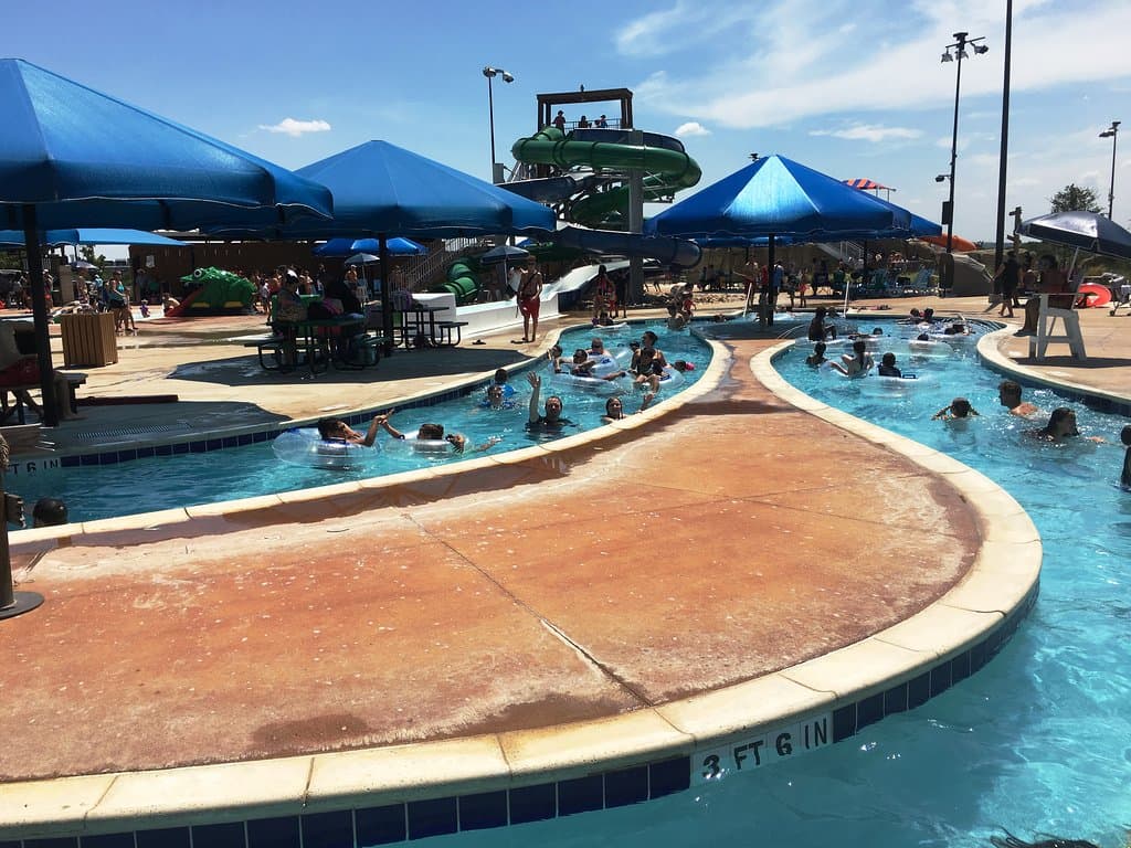 Picture of a portion of the waterpark. Lazy river in foreground, water slide in background.