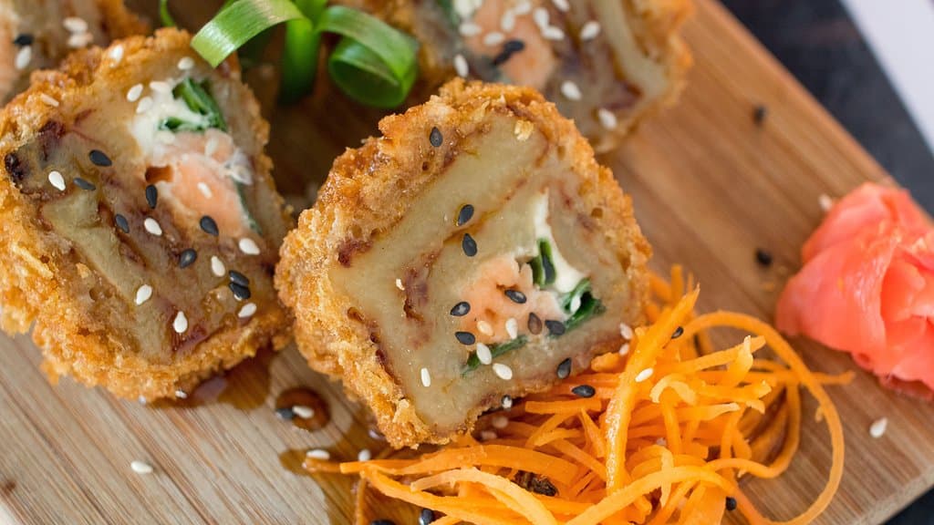 Pide tu rollo sin arroz envuelto en plátano maduro, salmón, cream cheese, puerro empanizado súper crunchy bañado en terriyaki. 