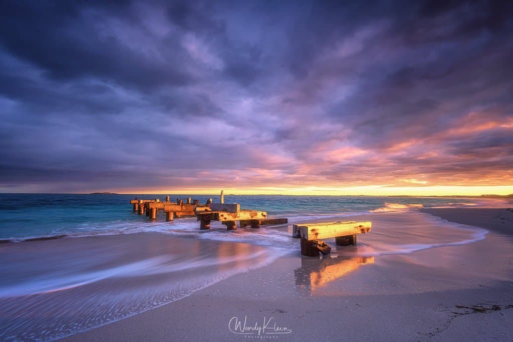 the sunlight hitting the old jetty remains at sunrise 