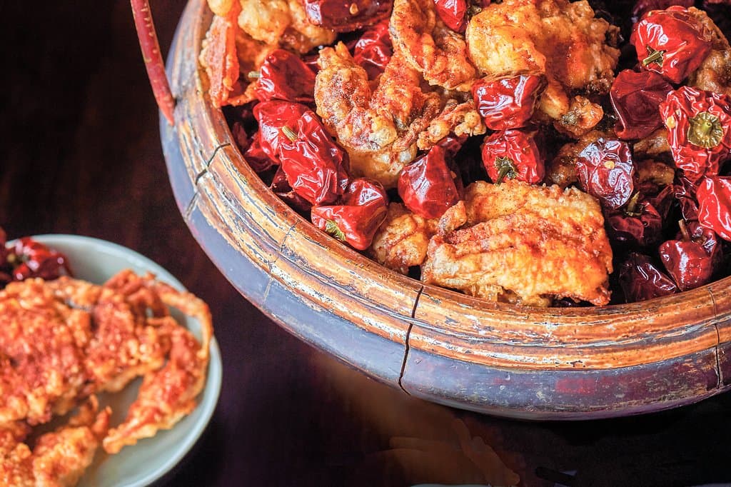 The signature Red Lantern is served to the table in a traditional Chinese wood basket overflowing with red Sichuan dried chilies. Crispy pieces of soft-shell crab nestle between them, infused with spices and lip-numbing chili essence. 