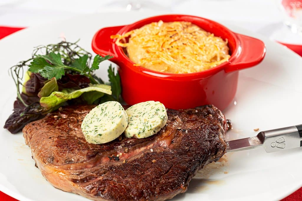 Entrecôte Angus Argentine poëlée, accompagnée d'un beurre maitre d'hotel, salade et son gratin de pomme de terre.