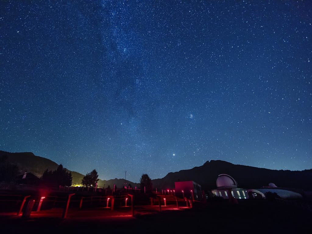 Il cielo stellato sopra l'Osservatorio Astronomico della Regione Autonoma Valle d'Aosta (www.oavda.it). A sinistra, in primo piano, le piazzole di osservazione nell'ampio giardino che circonda la struttura. A destra le cupole con i telescopi per le osservazioni di ricerca e le attività con scuole e pubblico. Credit: Giovanni Antico (www.gantico.com) per la Fondazione Clément Fillietroz-ONLUS