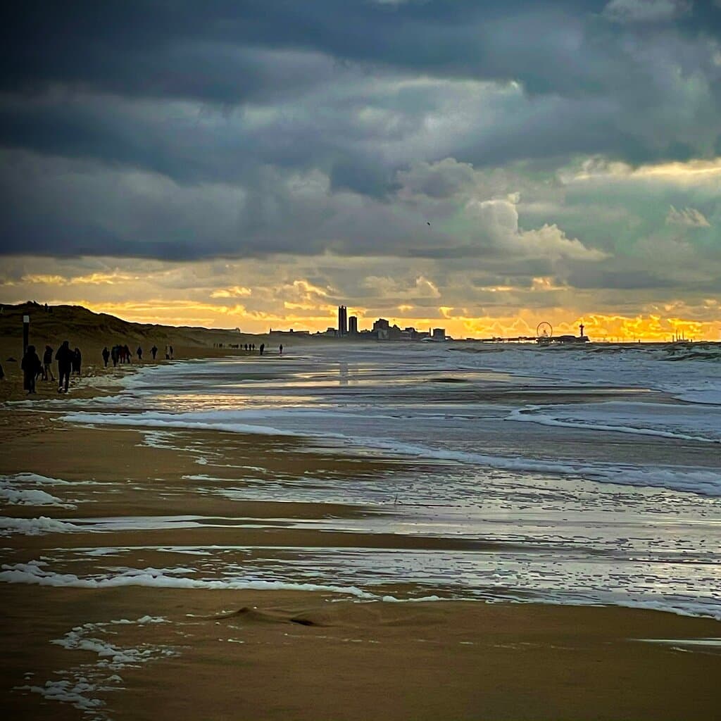 Klein strand bij hoge vloed, skyline van Scheveningen op de achtergrond