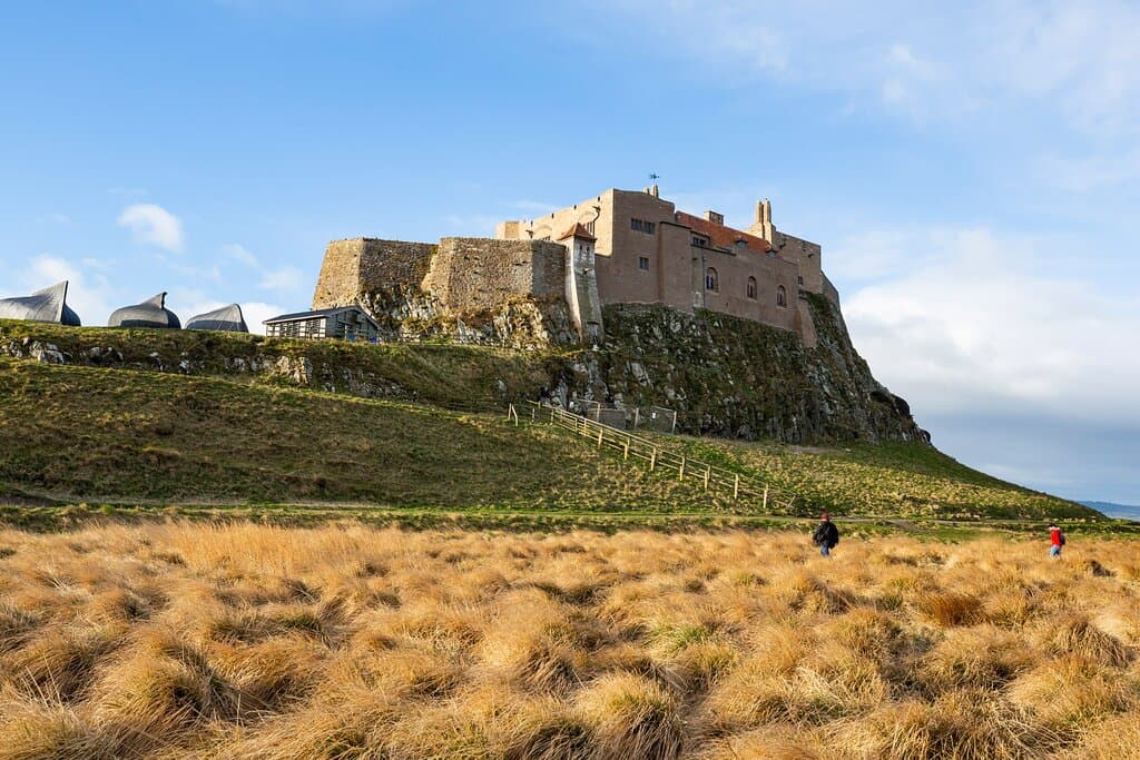 Lindisfarne castle viewed across the field, basking in sunshine