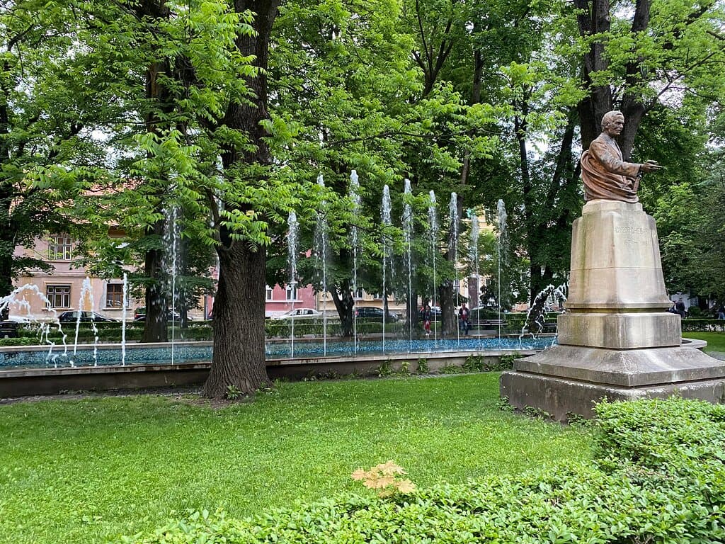 The fountain in the park and statue of Gheorghe Baritiu on the side. 