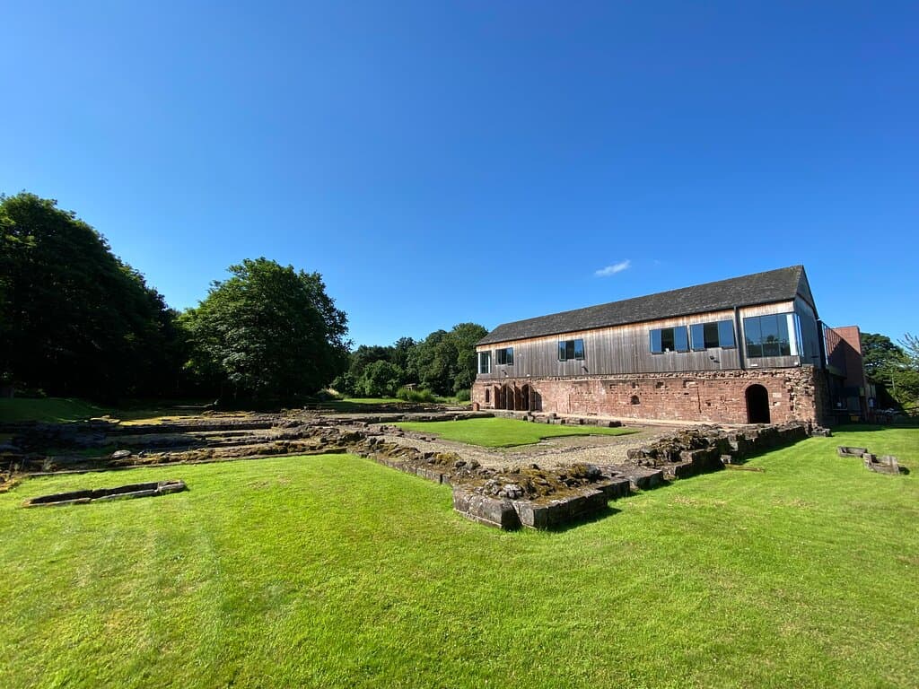 View looking towards the museum building, with the medieval undercroft at ground floor level and the archaeological remains of the priory in the foreground. 