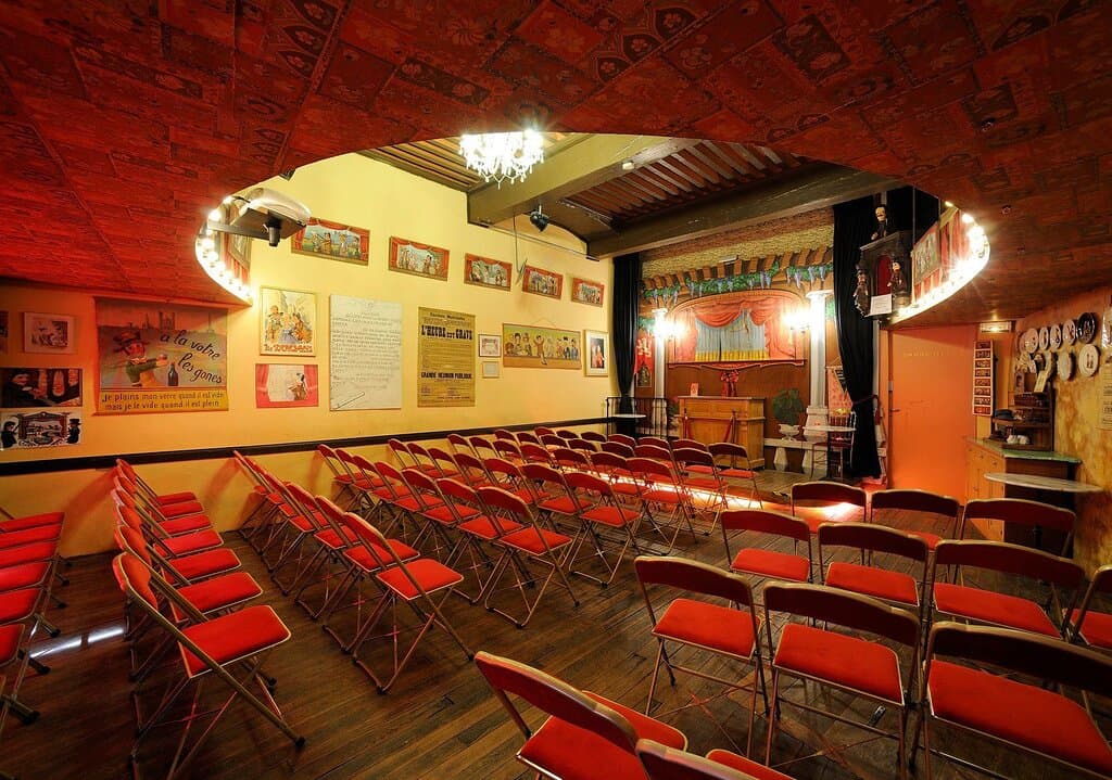 La Salle 1 !
Une pièce atypique et riche en décors. Vous pourrez apprécier les allusions et les affiches d'époques tout en assistant au spectacle de Guignol grâce à sa capacité de 100 places assises.

Mais n'oubliant pas les grands le soir, vous pourrez vous retrouvez le soir autour d'un verre et d'une planche de charcuterie tout en regardant une pièce de Café-Théâtre !

