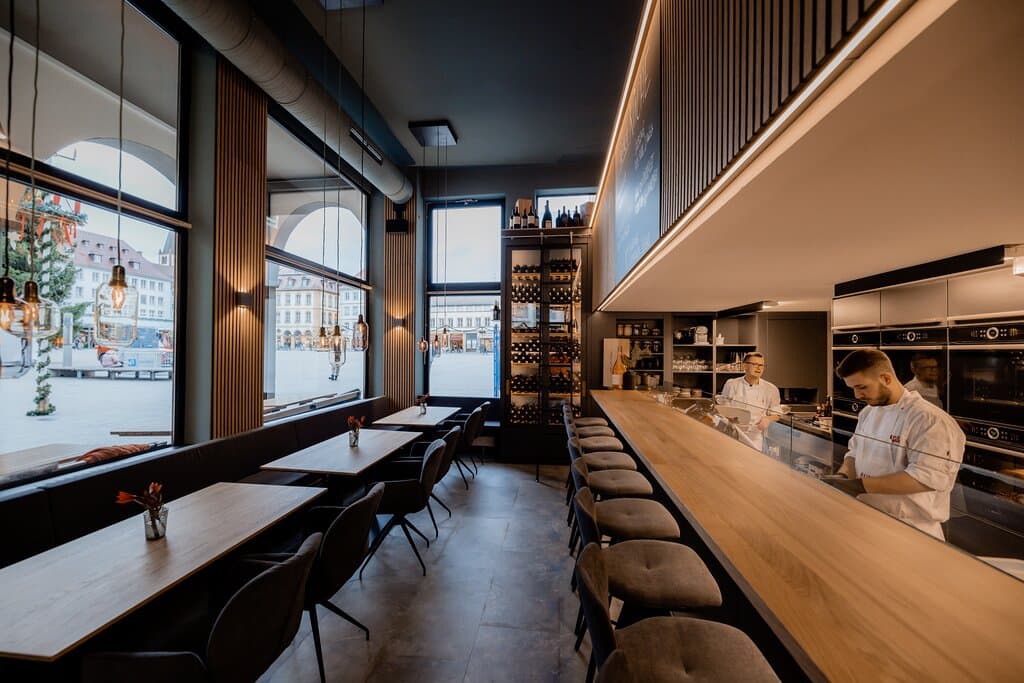 Kulinarischer Treffpunkt auf dem Marktplatz in Würzburg
„Ganz früher war in diesen Räumen die Würzburger Markthalle und dieser Gedanke hat mich inspiriert.“ (Bernhard Reiser)
„Aifach REISERS“ lässt sich mit einem Begriff oder einem einzigen Konzept nicht erfassen. Dieser Ort verändert im Laufe des Tages seine Stimmung, sein Angebot und natürlich auch seine Gäste: Ein genussvolles Fluidum also, eine Wandelbar, ein guter Ort für Würzburg.

Das „Aifach“ folgt einer komplett anderen gastronomischen 