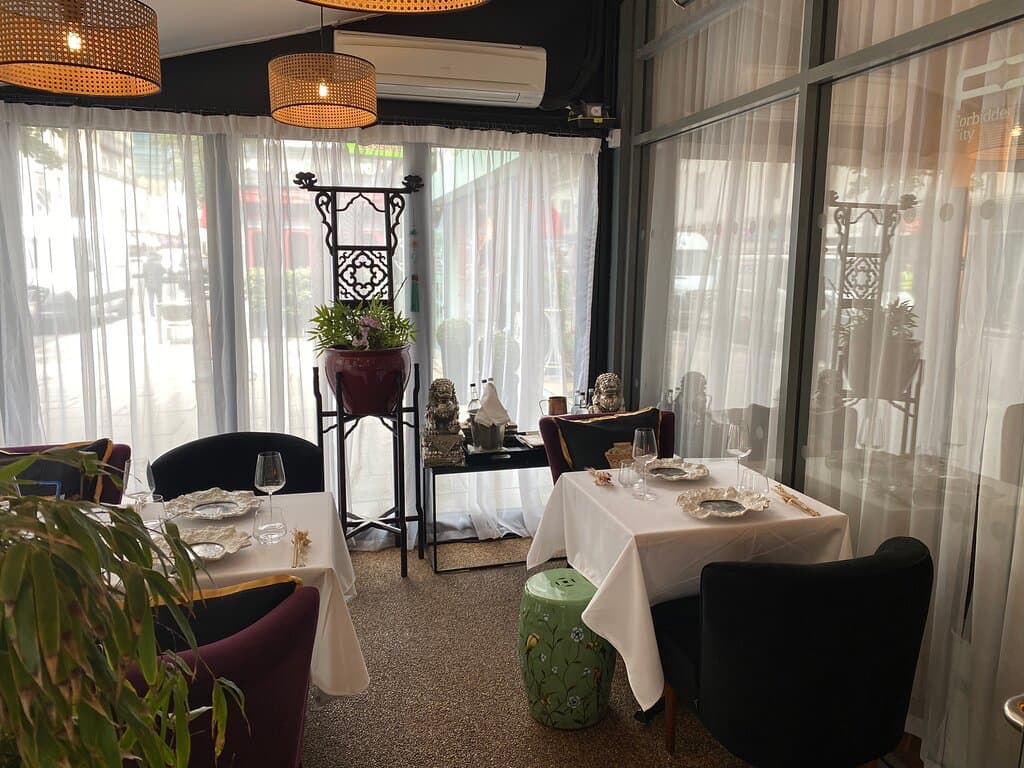 Glass of wine, dishes and part of menu.