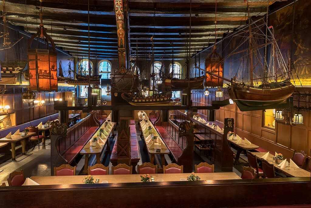 In der im 16. Jahrhundert erbauten Großen Halle sitzen Gäste auf den historischen Gelagebänken, die Lübecker Schiffer auch damals schon zum Feiern und für geschäftliche Treffen genutzt haben. Auch die detailgetreuen Schiffsmodelle, die im Großen Saal von der Decke hängen, sind Originale aus der Zeit der Hanse und wurden inzwischen liebevoll restauriert.