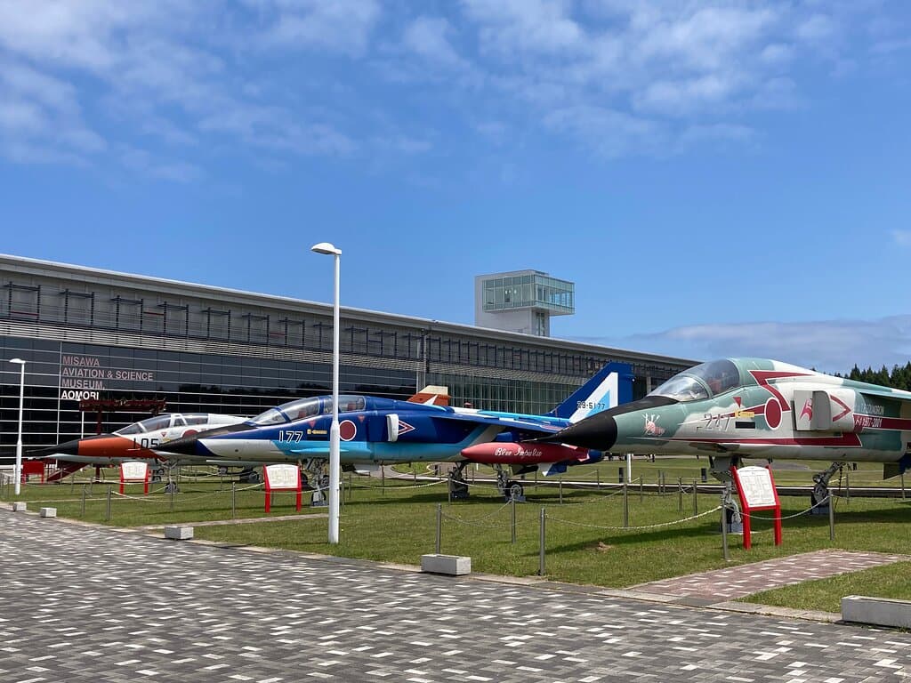 青森県立三沢航空科学館の外観。科学館前に広がる三沢市大空ひろばからの写真です。ひろばには自衛隊機、米軍用機11機の実機が展示してあります。