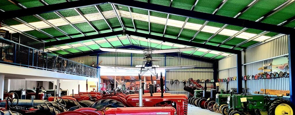 1929 Simmons Spartan Biplane is on Display, hovering above a vast array of Tractors and at the perfect viewing height from the Mezzanine Floor housing collections of Vintage memorabilia including that of Cameras and a life size Vintage Store display and '70s themed display.