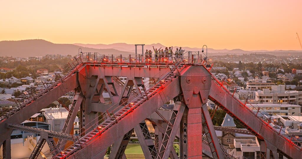 A group of climbers celebrating at the top of the bridge on a Twilight Climb.