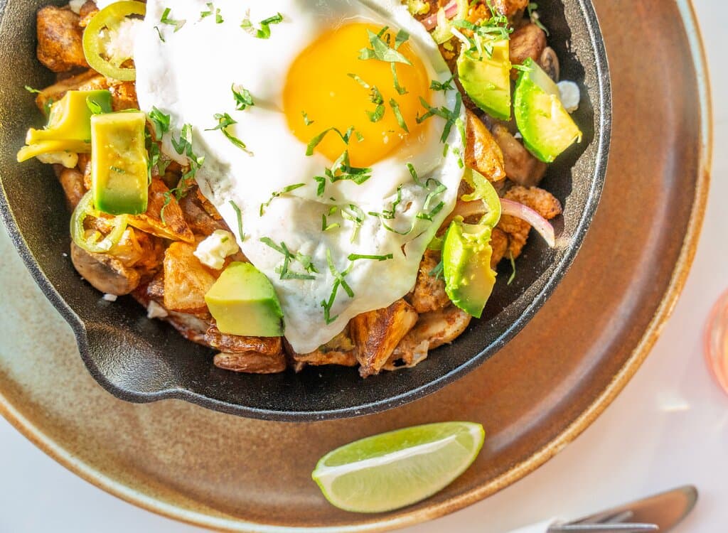 SOUTHWEST CHORIZO HASH  Roasted red potatoes tossed with crumbled chorizo, sweet corn, pinto beans, mushrooms, peppers, and onions. Topped with salsa roja, avocado, pickled jalapeños, feta, fresh cilantro, and a sunny side egg.