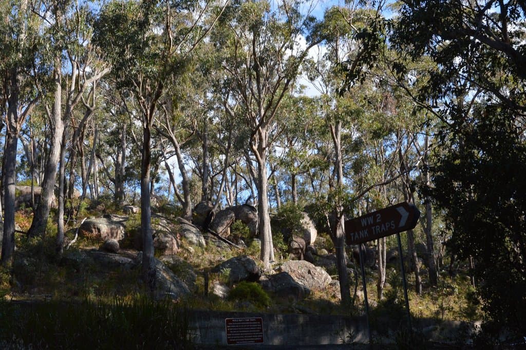 Road sign at site and concrete retaining wall to prevent road by passing