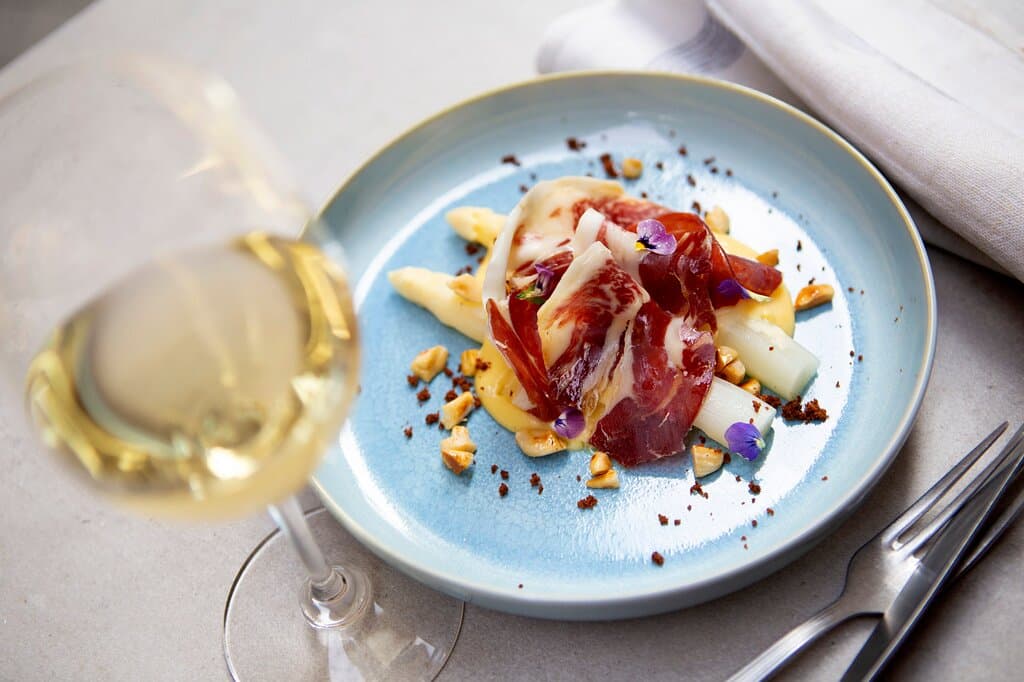 Espárragos blancos con salsa holandesa, jamón ibérico, mantequilla dorada y almendras macon. White asparagus with sauce hollandaise, Iberico ham, browned butter and macon almonds
