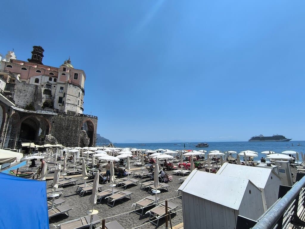 Una giornata estiva sulla spiaggia attrezzata comunale: ombrelloni ordinati, sabbia pulita e un mare cristallino per una vacanza senza pensieri.